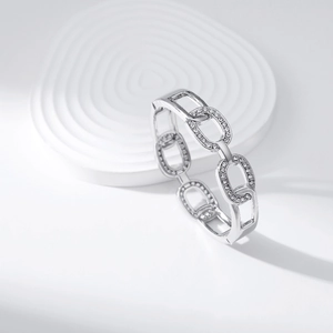 Detail of silver chain link bracelet with pave cubic zirconia on white display stand