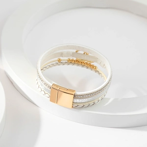 Close-up of white braided leather bracelet with gold beads and magnetic clasp detail