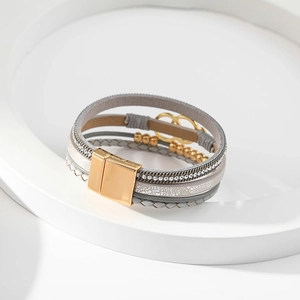 Detail of multi-layer grey braided leather bracelet with golden rings and crystal beads