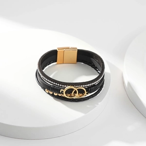 Detail of multi-layer black leather bracelet with interlocking gold rings and rhinestones