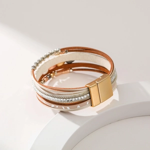 Detail of bohemian multilayer leather bracelet with leaf charms and magnetic metal clasp