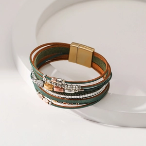 Detail of bohemian multilayer leather bracelet featuring leaf charms and magnetic clasp