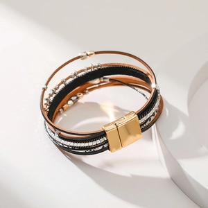 Detail of multi-layer leather wrap bracelet featuring leaf charms and gold magnetic clasp