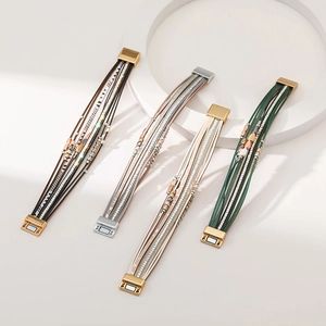 Bohemian multilayer leather bracelet with leaf charms and magnetic clasp on white stand