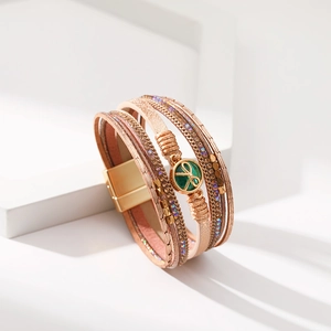 Dettaglio del bracciale multistrato in pelle con catene oro rosa, gemma verde e chiusura magnetica
