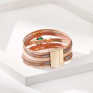 Dettaglio di bracciale multistrato in pelle oro rosa con gemma verde e chiusura magnetica