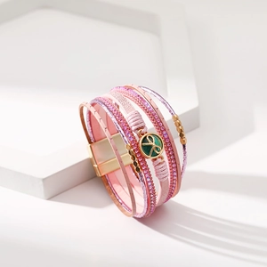 Dettaglio di bracciale multi-strato in pelle con ciondolo verde e chiusura magnetica