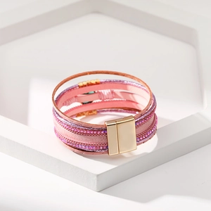 Dettaglio di un bracciale multistrato in pelle rosa con strass e chiusura magnetica