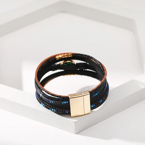 Dettaglio del bracciale multistrato in pelle con strass blu e chiusura magnetica dorata