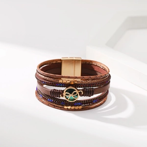 Dettaglio del bracciale multistrato in pelle marrone con chiusura magnetica dorata e cristalli