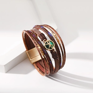Macro del bracciale multistrato in pelle bohemian con fiocco dorato e chiusura magnetica