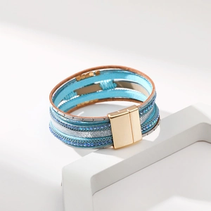 Dettaglio del bracciale bohémien multistrato in pelle con strass blu e fibbia magnetica