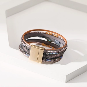 Dettaglio del bracciale bohémien multistrato in pelle con strass brillanti e chiusura magnetica oro