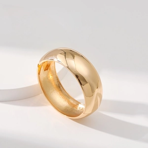 Minimalist wide gold mirror-polished cuff bracelet on geometric white pedestal display