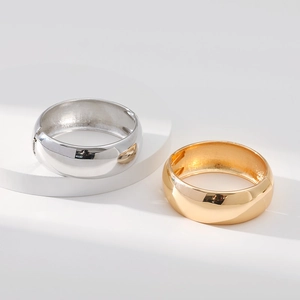 Polished gold and silver wide drum bangles with a glossy mirror finish on a display