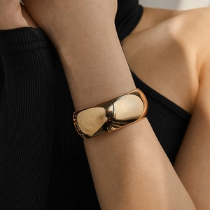 Polished gold wide drum cuff bracelet with reflective mirror finish worn on wrist