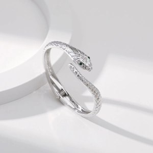 Dettaglio macro del bracciale a serpente d'argento con occhi verdi e scaglie testurizzate