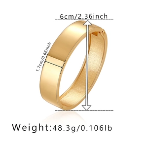 Dettaglio di un ampio bracciale dorato lucido a specchio con dimensioni e peso
