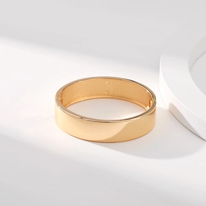 Dettaglio del bracciale rigido dorato lucido con superficie a specchio minimalista
