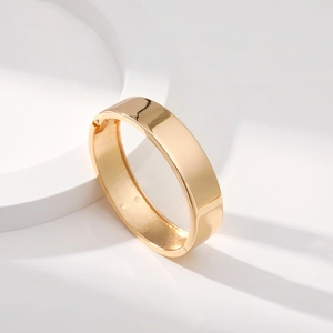 Bracciale rigido dorato minimalista con finitura lucida a specchio su podio bianco
