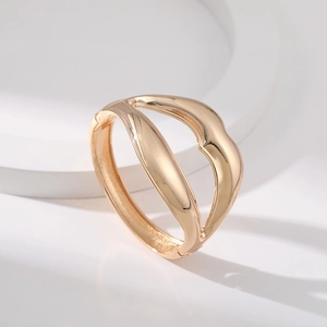 Detailed view of a gold-toned lip-shaped bangle with smooth curves and polished metal finish