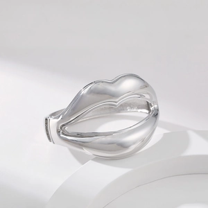 Detailed view of silver lip-shaped alloy bracelet on a white geometric display
