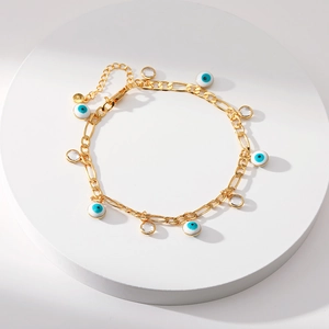 Detail van de gouden enkelband met blauw boze oog en kristallen op wit voetstuk