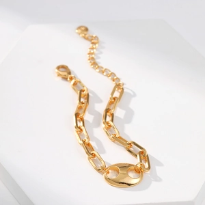 Polished gold link chain bracelet with coffee bean link on geometric display