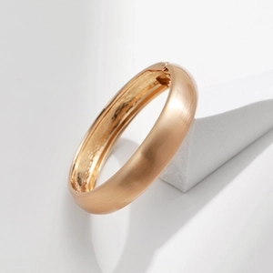 Gros plan sur un bracelet doré avec finition brossée mate et fermoir à charnière pratique