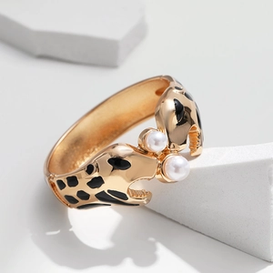 Detailansicht eines goldenen Leoparden-Armreifs mit Emaille-Punkten und weißen Perlen