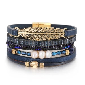 Détail du bracelet bohème multicouche avec plume dorée et perles blanches sur cuir bleu
