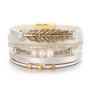 Détail d'un bracelet multicouche bohème avec breloque plume dorée et fermoir aimanté