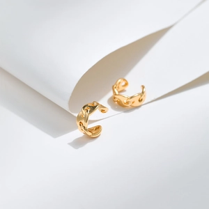 Minimalist gold chain link ear bone cuffs displayed on elegant white geometric backdrop