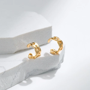 Minimalist gold Cuban chain link ear cuffs displayed on a white marble stone