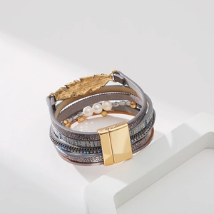 Détail d'un bracelet en cuir multicouche bohème avec breloque feuille et fermoir magnétique