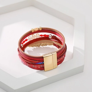 Détail du bracelet multicouche en cuir bohème avec perles rouges et breloque feuille