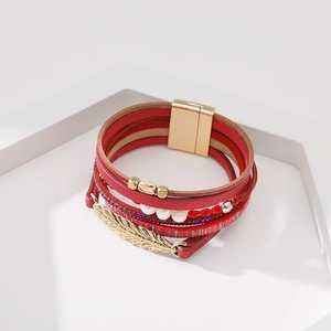 Détail du bracelet multicouche en cuir rouge avec breloque feuille dorée et perles