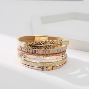 Détails du bracelet multicouche bohème avec plume dorée et perles sur fond blanc