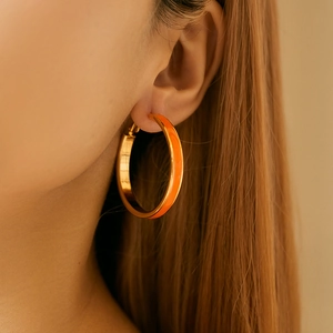Retro 18K vergoldete Creolen mit orangefarbenem Emaille an Model im Sonnenlicht