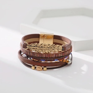 Détail du bracelet bohème multicouche en cuir avec breloque feuille et fermoir magnétique
