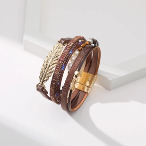 Détail d'un bracelet multicouche en cuir bohème avec breloque feuille et perles nacrées