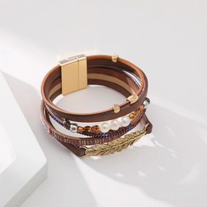 Détail d'un bracelet multicouche en cuir bohème avec perles et breloque feuille sur socle
