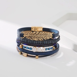Détail d'un bracelet multicouche bohème avec breloque feuille dorée et perles bleues