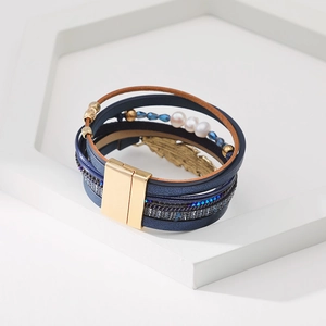 Détail du bracelet bohème multicouche en cuir avec plume dorée et perles bleues