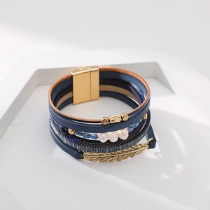 Détail d'un bracelet bohème multicouche en cuir avec perles et breloque feuille d'or