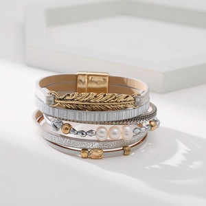 Détail d'un bracelet bohème multicouche avec breloque feuille d'or, perles et fermoir aimanté