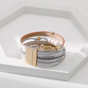 Détail d'un bracelet bohème à plusieurs rangs avec perles, plume et fermoir magnétique