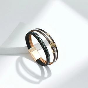 Detail eines mehrlagigen Lederarmbands mit grünen Perlen und goldenem Magnetverschluss