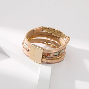 Détail d'un bracelet de style bohème multicouche en cuir avec fermoir aimanté et plume