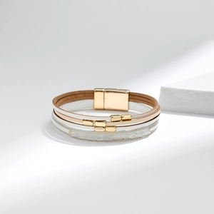 Detailaufnahme des mehrlagigen Lederarmbands in Weiß und Braun mit goldenem Magnetverschluss